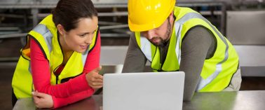 Male and female workers using laptop in factory